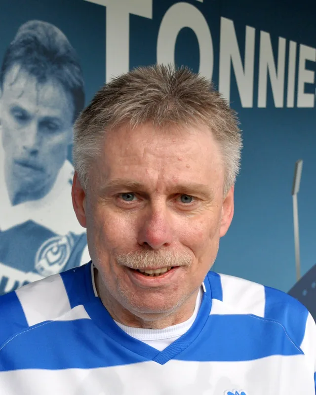 Michael Tönnies lächelt im MSV-Trikot vor einer Wand mit seinem Namen